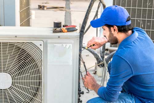 A technician performs repairs on a large A/C unit